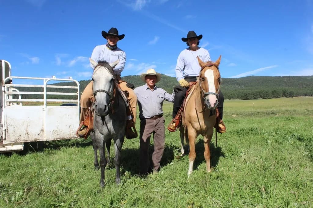 Three Pacheco ranchers with horses on open pasture